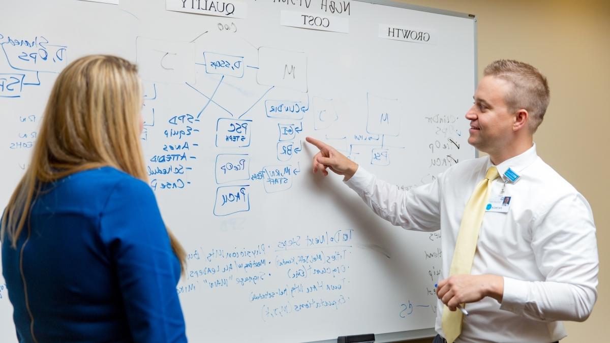 Alumni Patrick Halinsky uses a white board to map a process at a local hospital.